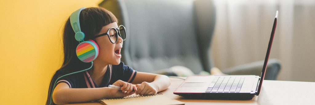 Girl with glasses smiling at a laptop